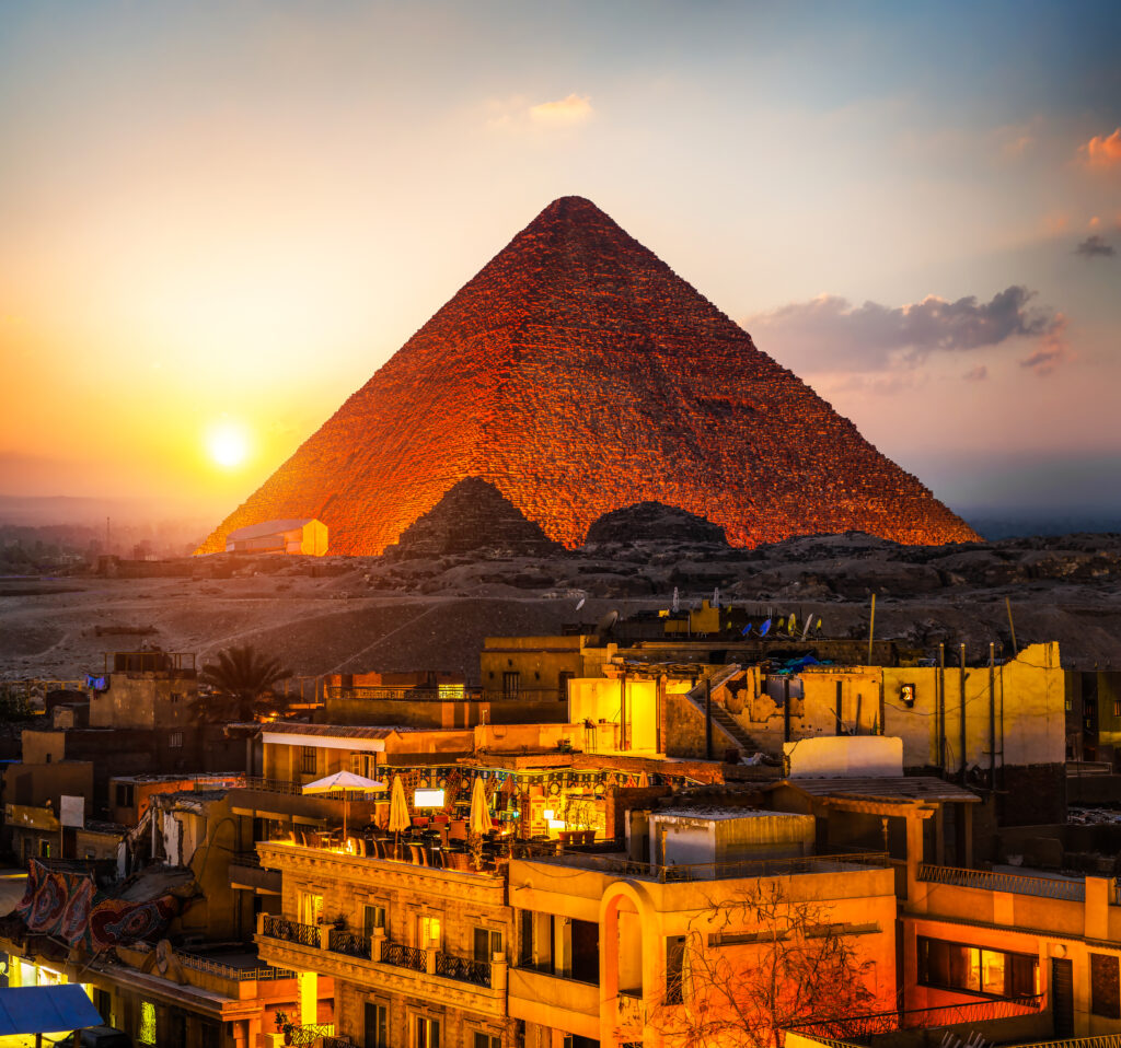 Cultural travel experience in Egypt featuring the Great Pyramid of Giza at sunset overlooking Cairo cityscape