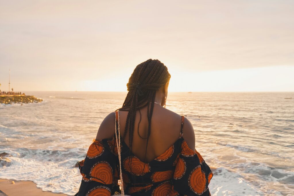 Woman standing on a beach looking out over the ocean at sunset