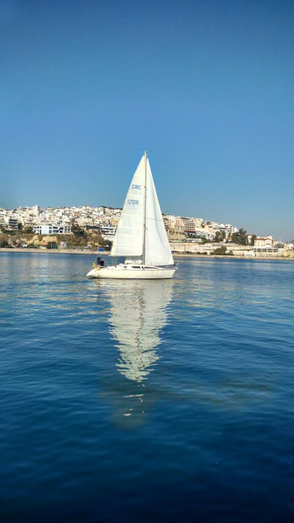 White sailboat on blue water along the Athens coast in Greece